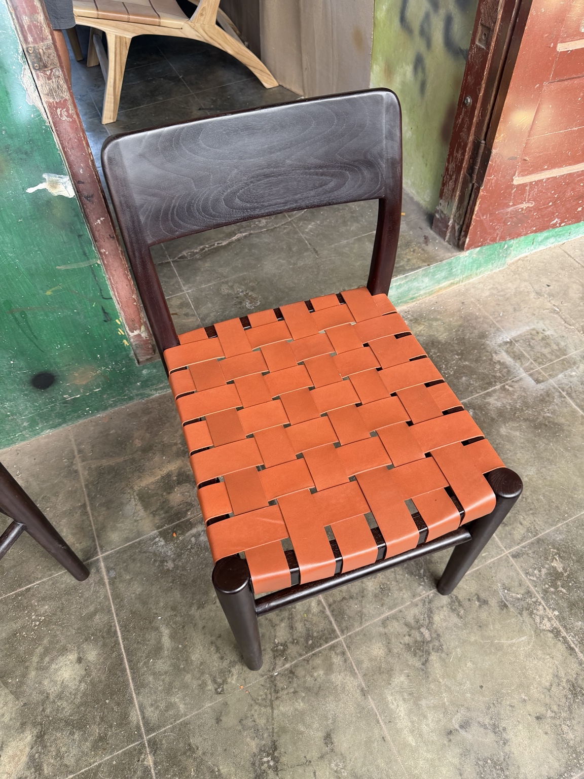 Detail van de originele stoel met oranje gevlochten leer en een donker houten frame